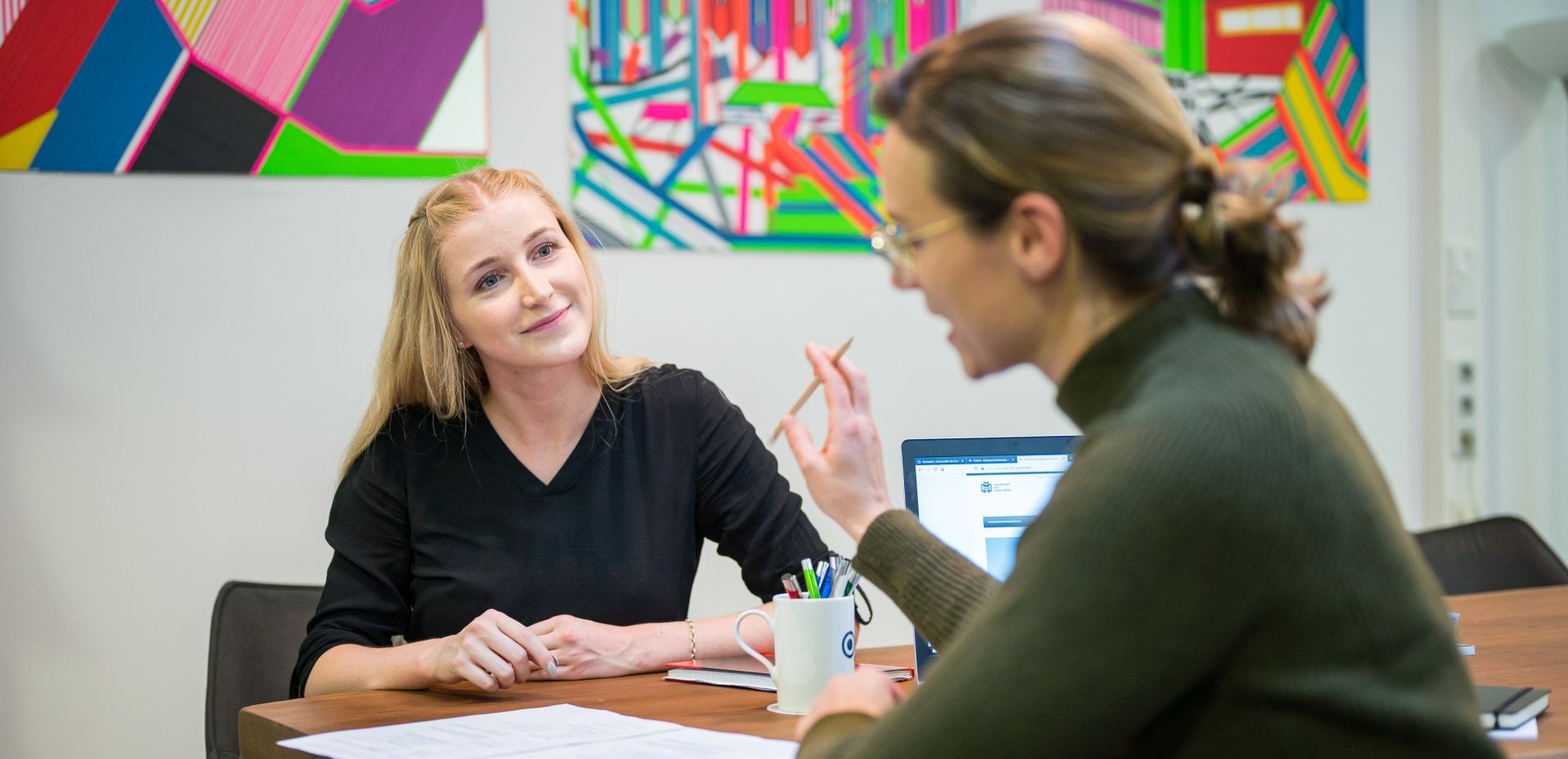 Zwei Frauen sitzen sich beratend ein einem Büro gegenüber