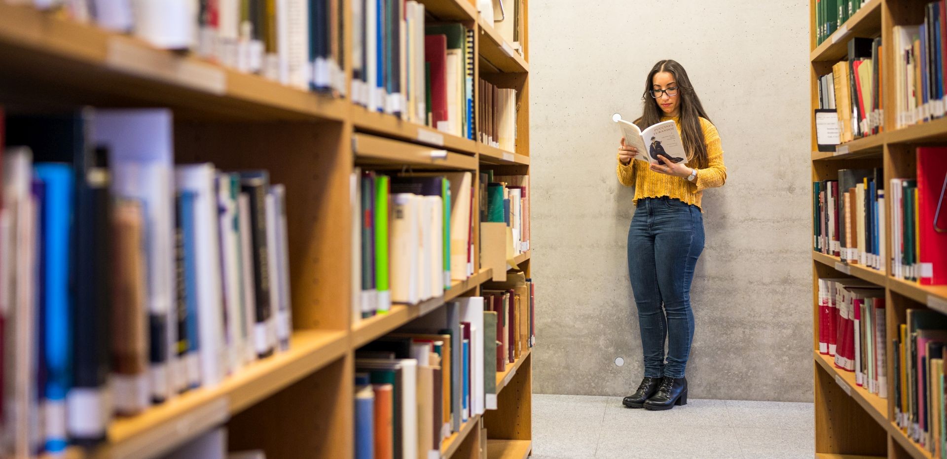 lesende Studentin zwischen zwei Bücherregalen