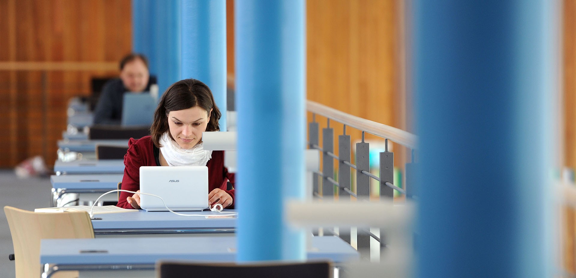 Studentin arbeitet mit ihrem Laptop an einem Schreibtisch in der Bibliothek