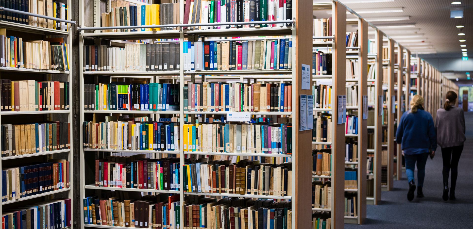 Bücherregale in einer Bibliothek mit Studenten im Gang