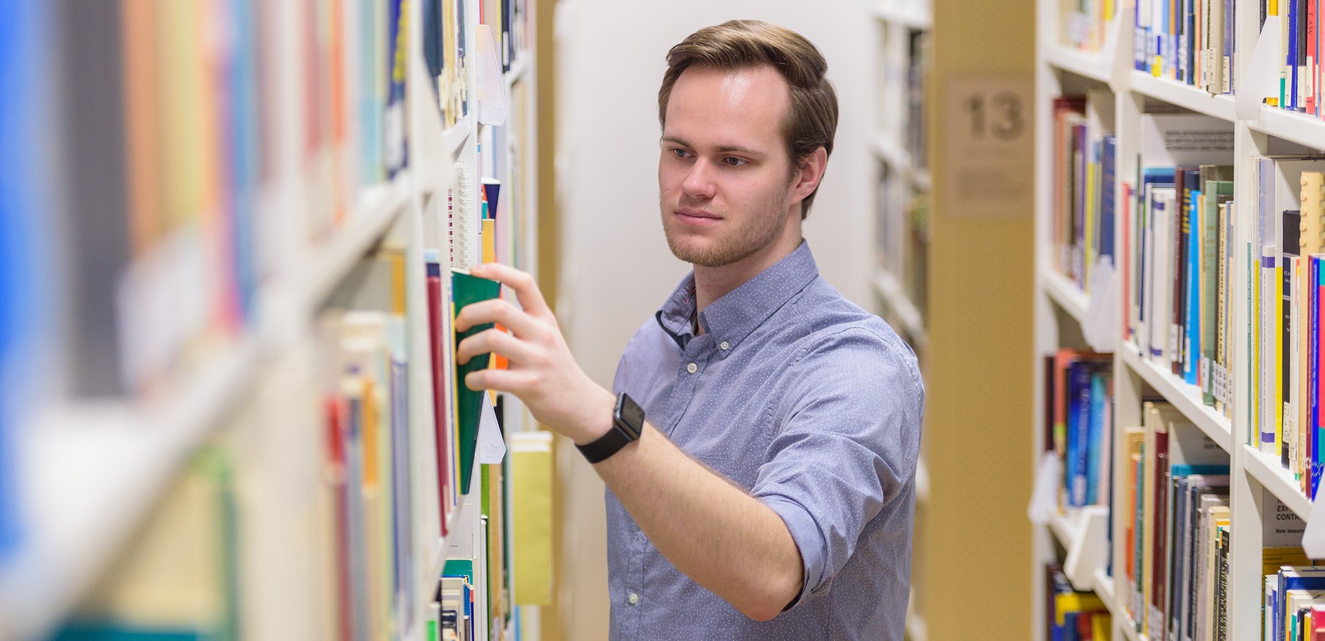 Student zwischen zwei Bücherregalen