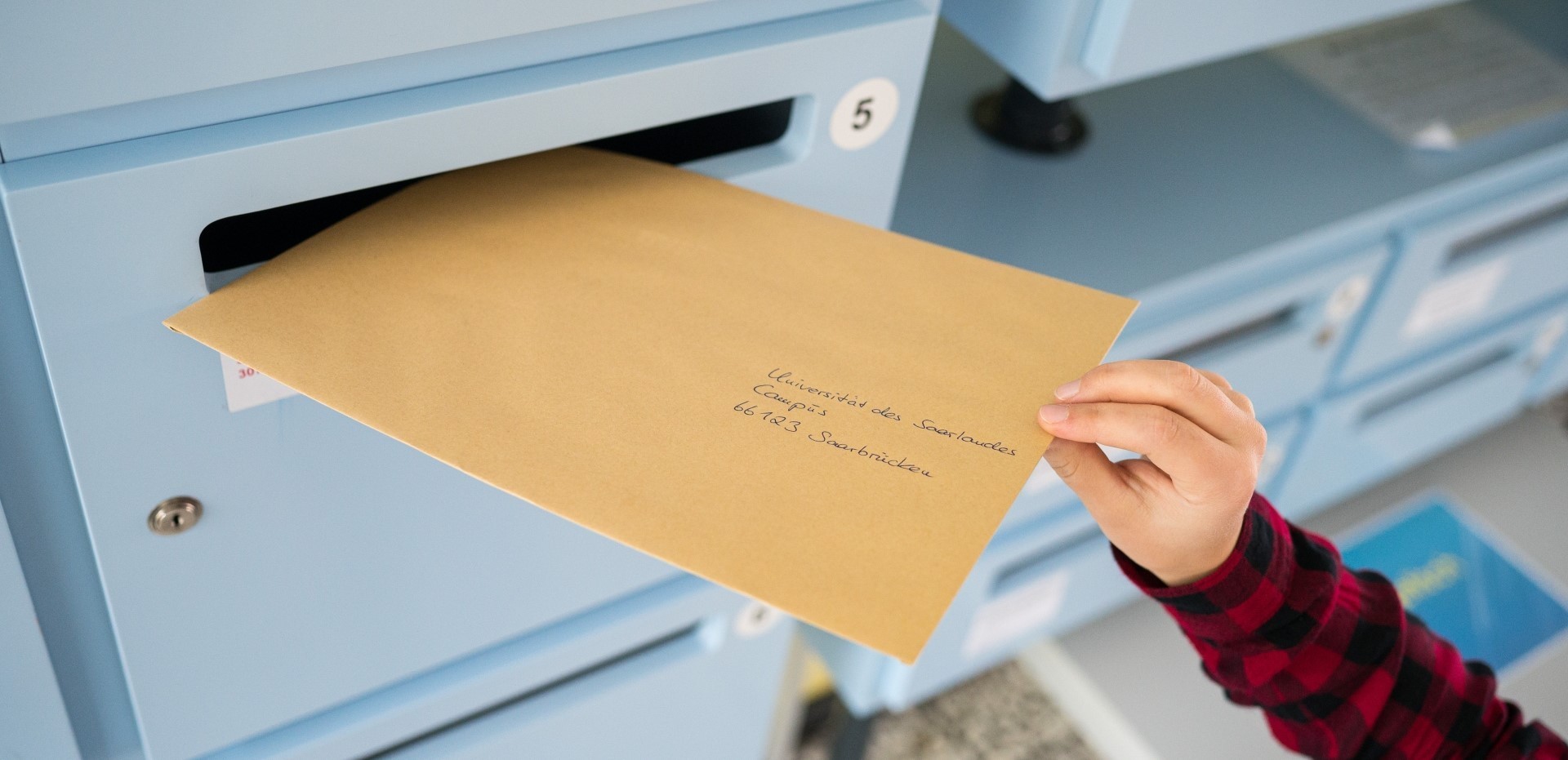 Ein an die Universität des Saarlandes adressierter Brief wird in einen Breifkasten geworfen