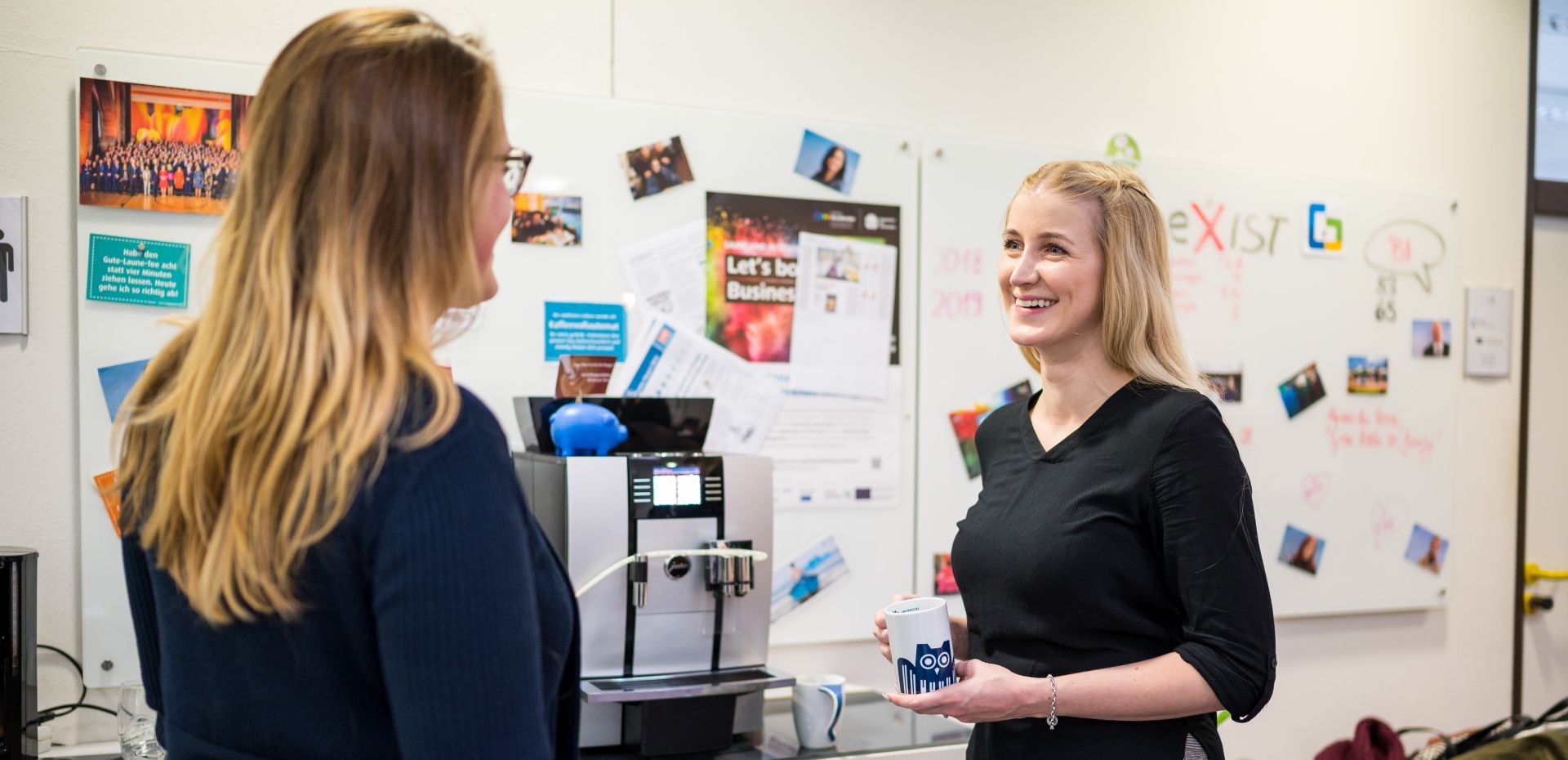 Zwei Frauen unterhalten sich am Kaffeeautomaten