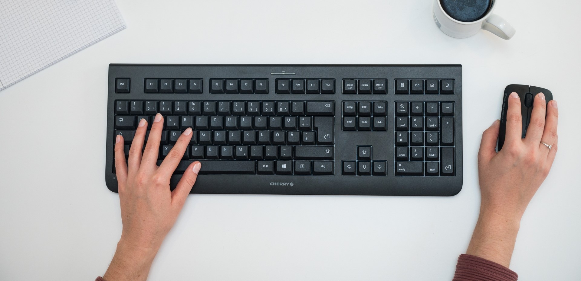 Draufsicht auf eine Tastatur, Maus und zwei Hände