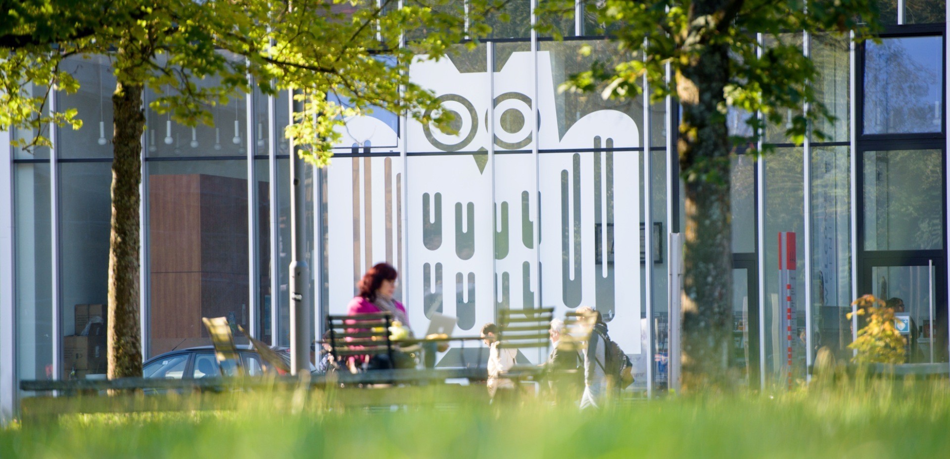 Ausschnitt eines Glasbaus mit großem weißen Logo der Universität des Saarlandes auf den Fenstern