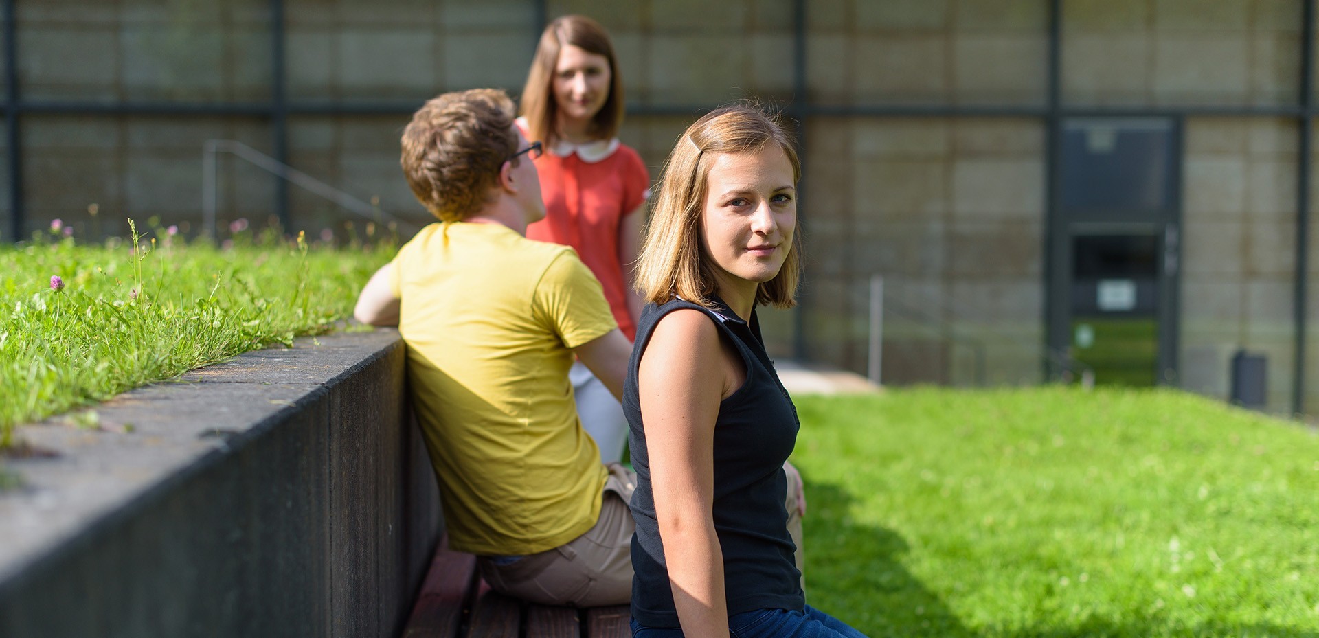 Studenten sitzen hintereinander auf einer Bank