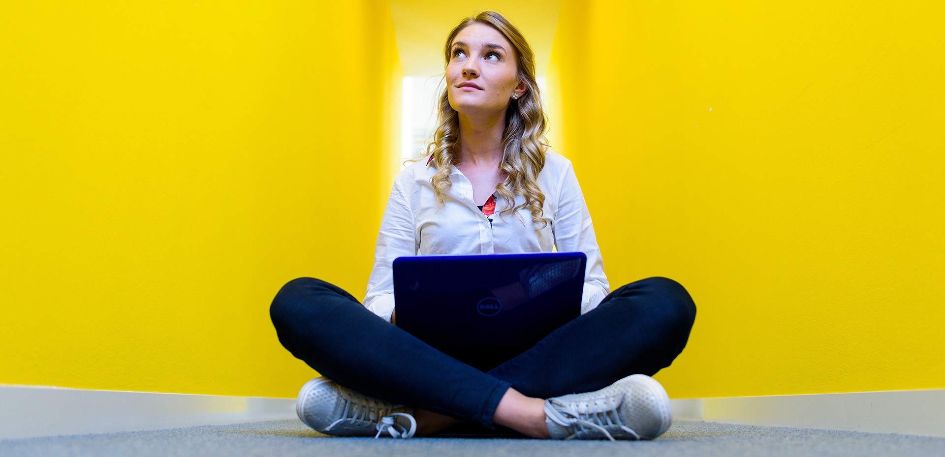 Studentin im Schneidersitz mit einem Laptop