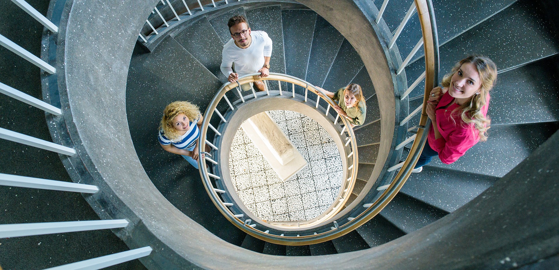 Aufsicht auf eine Wandeltreppe, in der vier Studierende stehen 