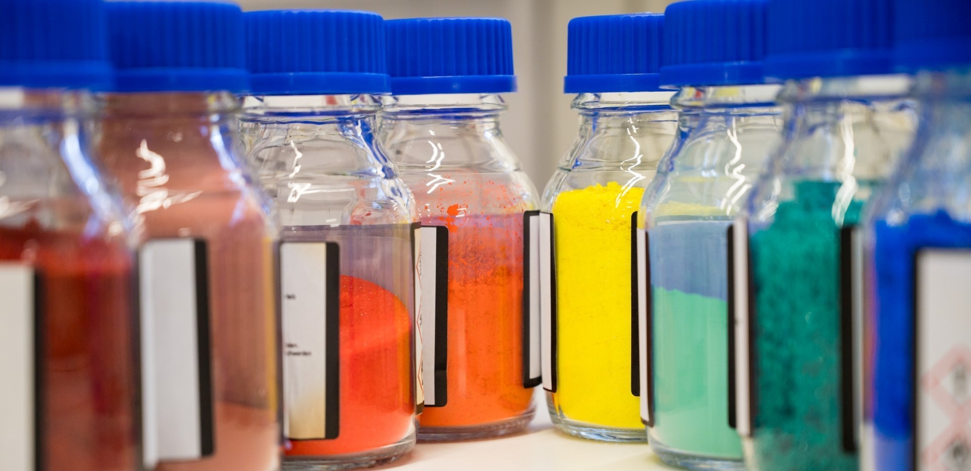 mehrere kleine Flaschen im Chemielabor mit farbigem Pulver