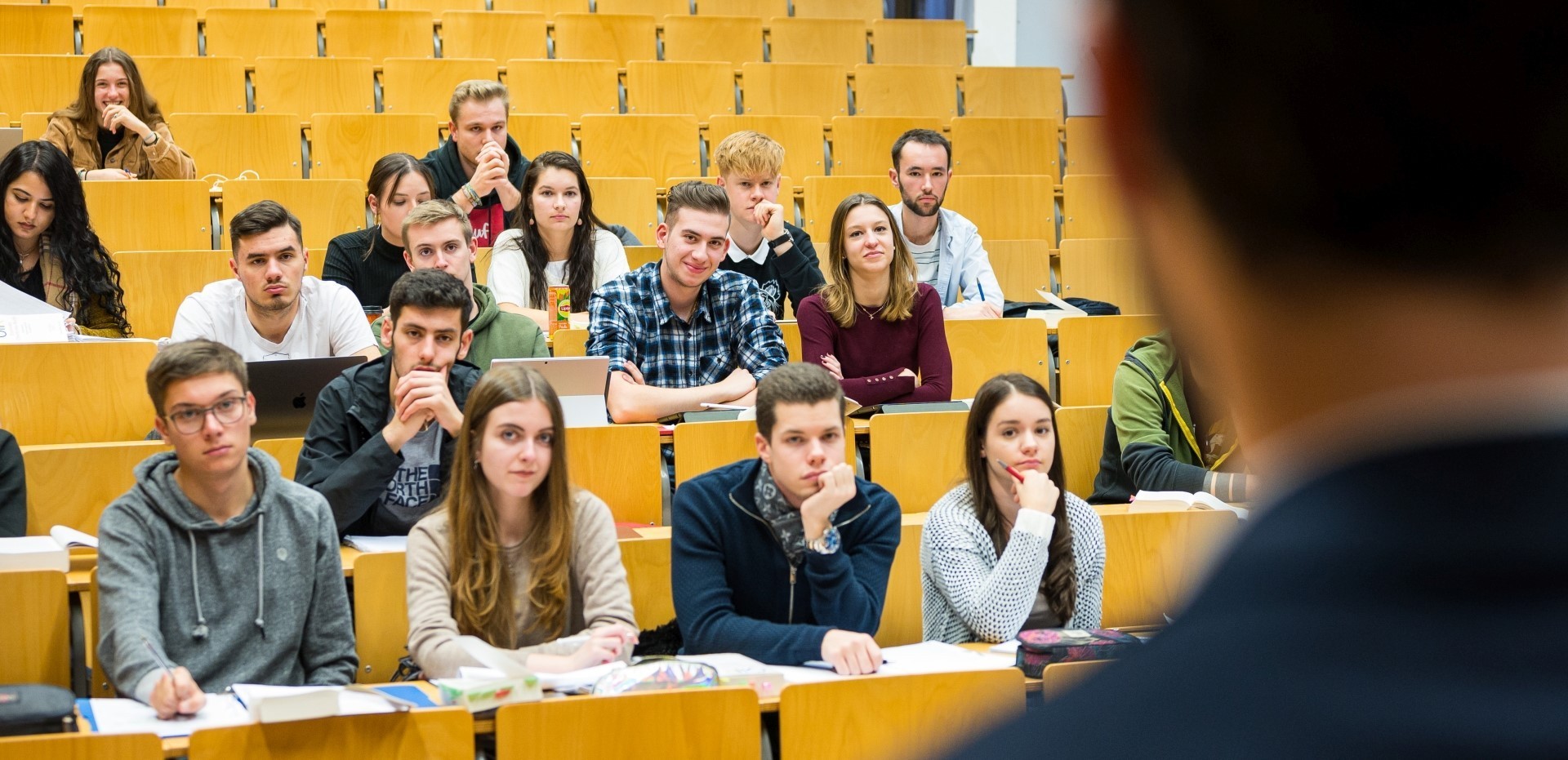 Dozent steht vor Studierenden in einem Hörsaal