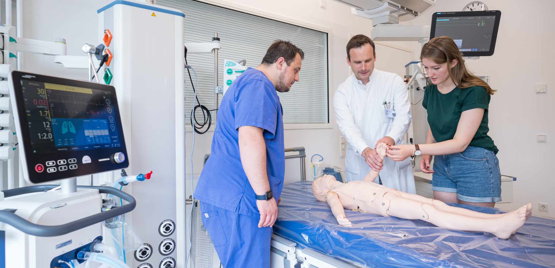 Zwei Ärzte und eine Studentin untersuchen eine Dummy-Puppe