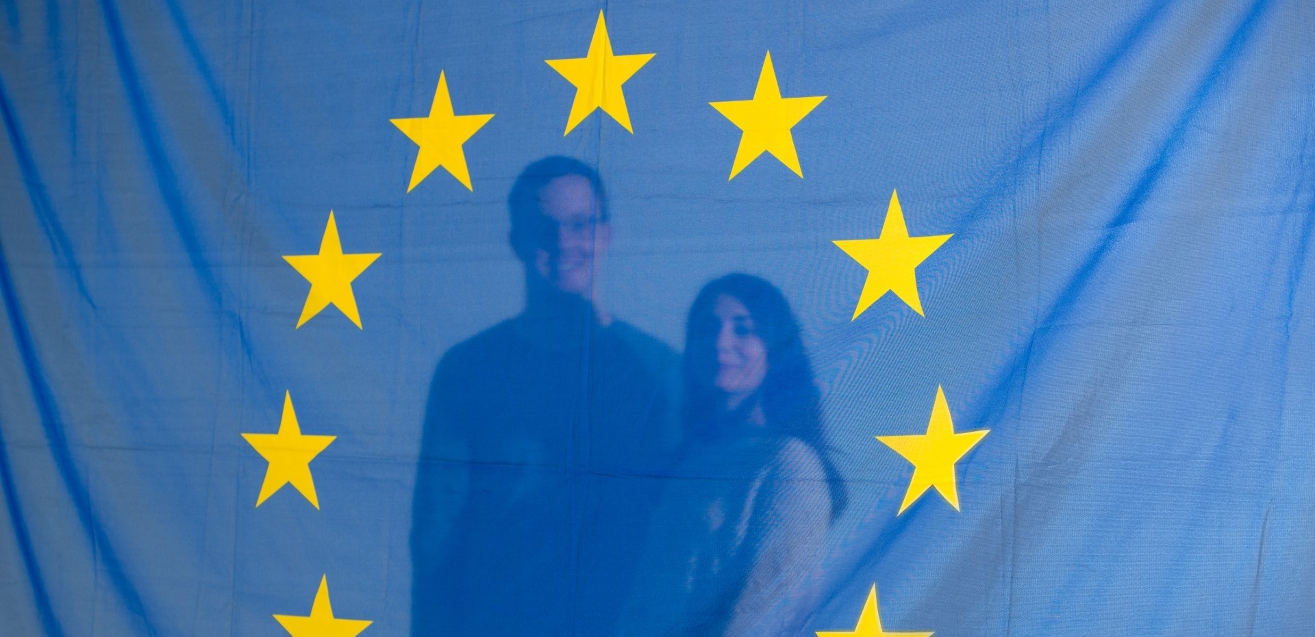 Zwei Studierende stehen hinter einer Europaflagge