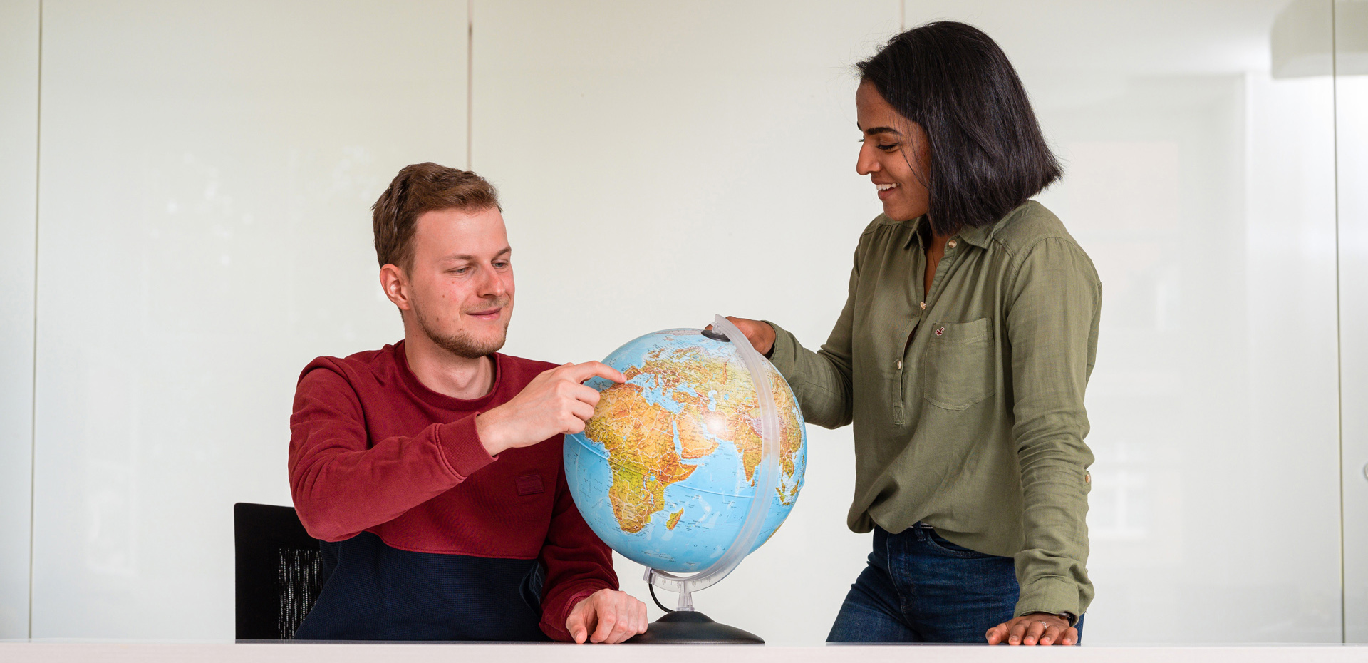 Ein junger Mann und eine junge Frau betrachten einen Globus.