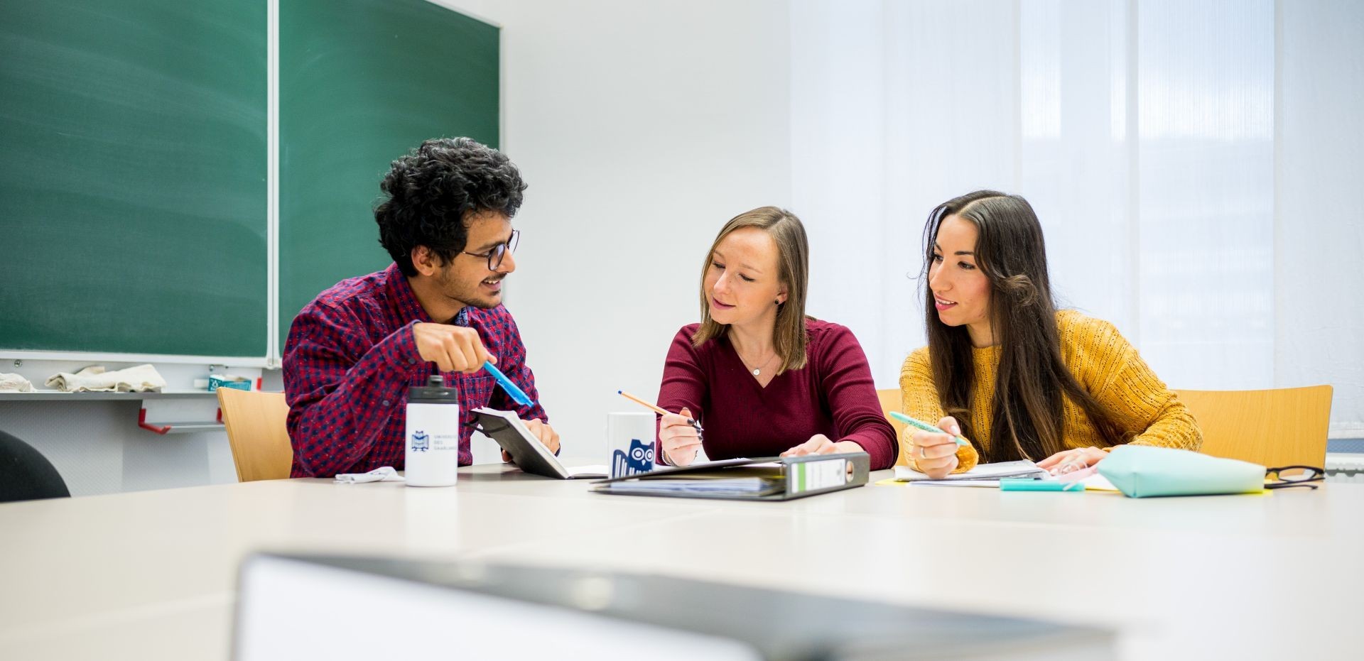 Studierende sitzen in einem Seminarraum und unterhalten sich