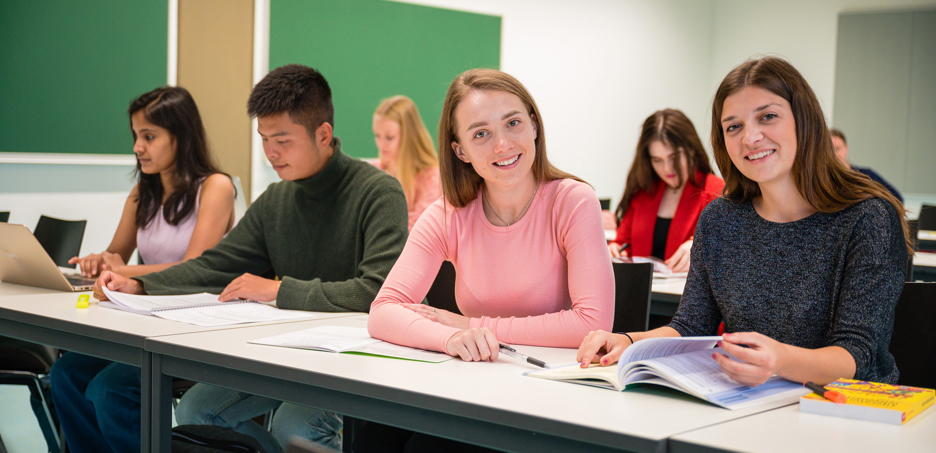 Zwei Studentinnen im Seminar schauen in die Kamera.