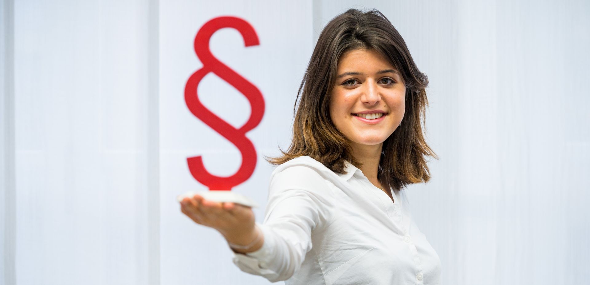 Studentin hält ein großes Paragraphenzeichen in der Hand